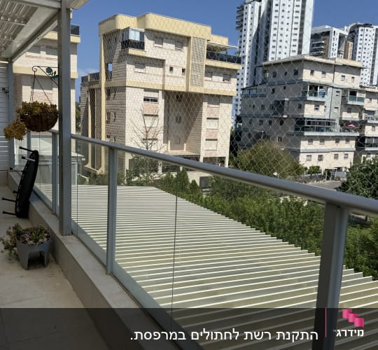 מרפסת עם רשת נגד יונים ונוף לבניינים